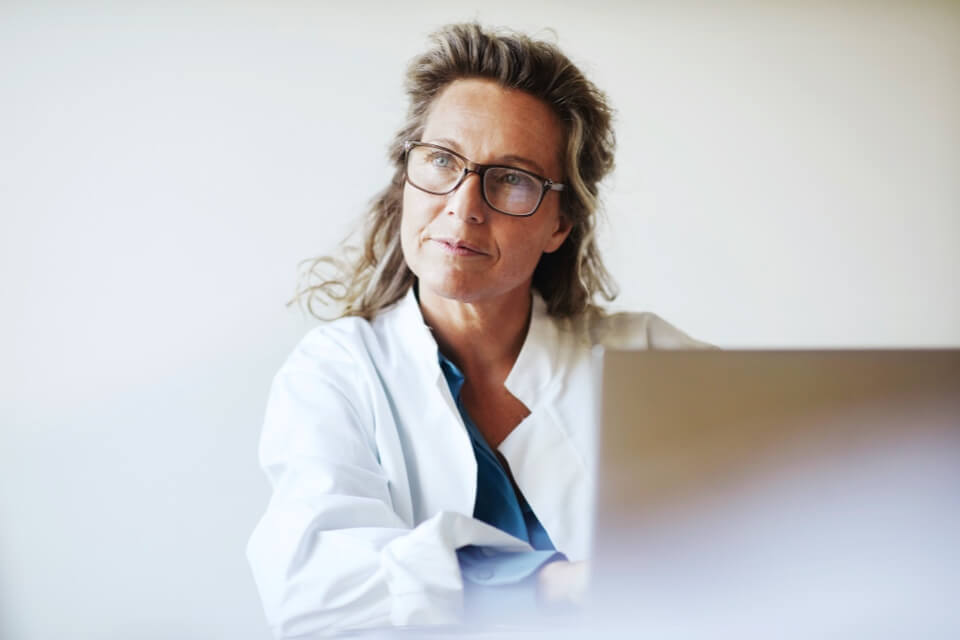 Female doctor wearing glasses using laptop