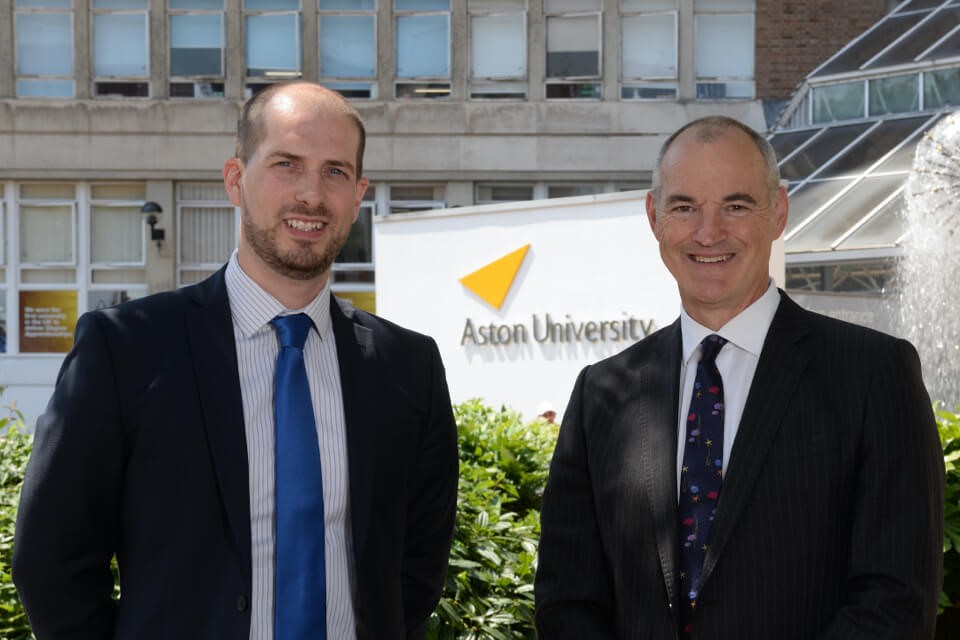 Two smiling males in front of Aston University sign