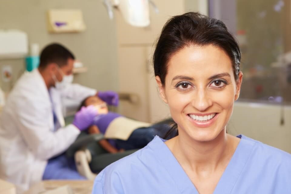 Smiling female dentist with male assistant working on a young patient