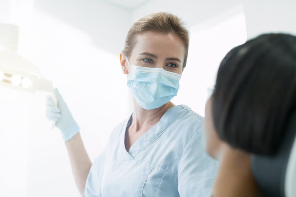 Female dentist wearing a mask with patient