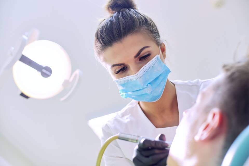 Female dentist in mask treating patient