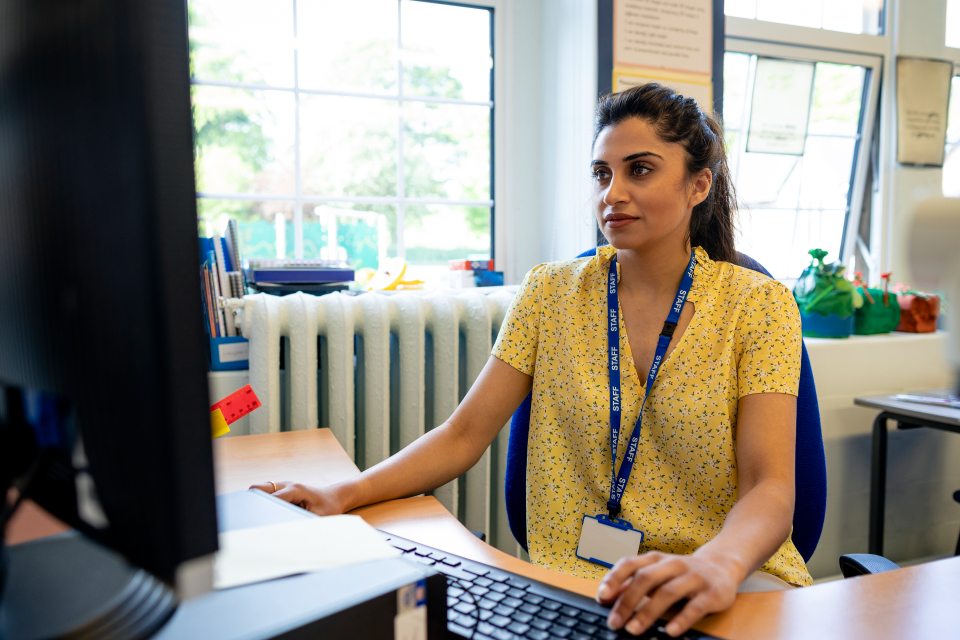 Female doctor sat at desk by window using a computer