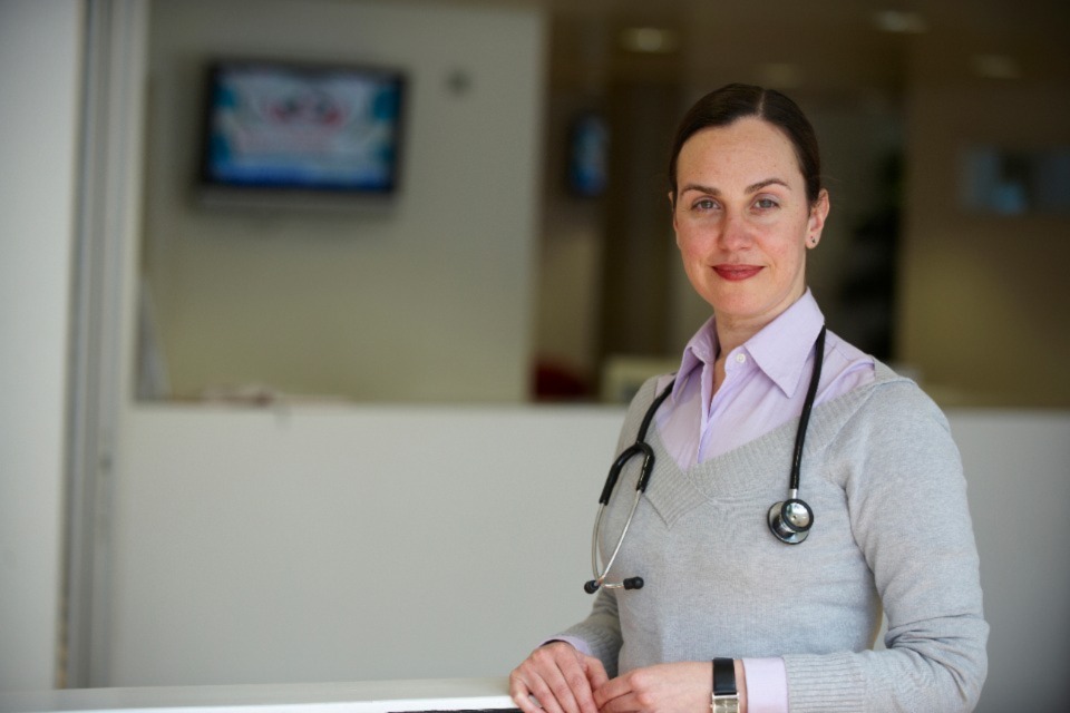 Female medical professional standing in corridor with a black stethoscope