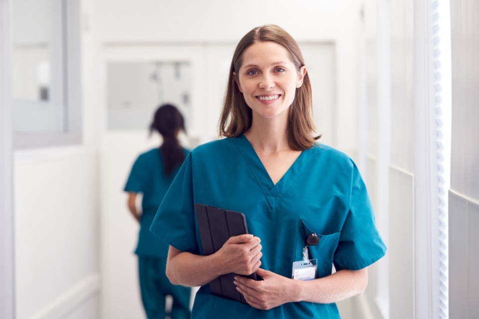 Female medical professional holding tablet standing in corridor