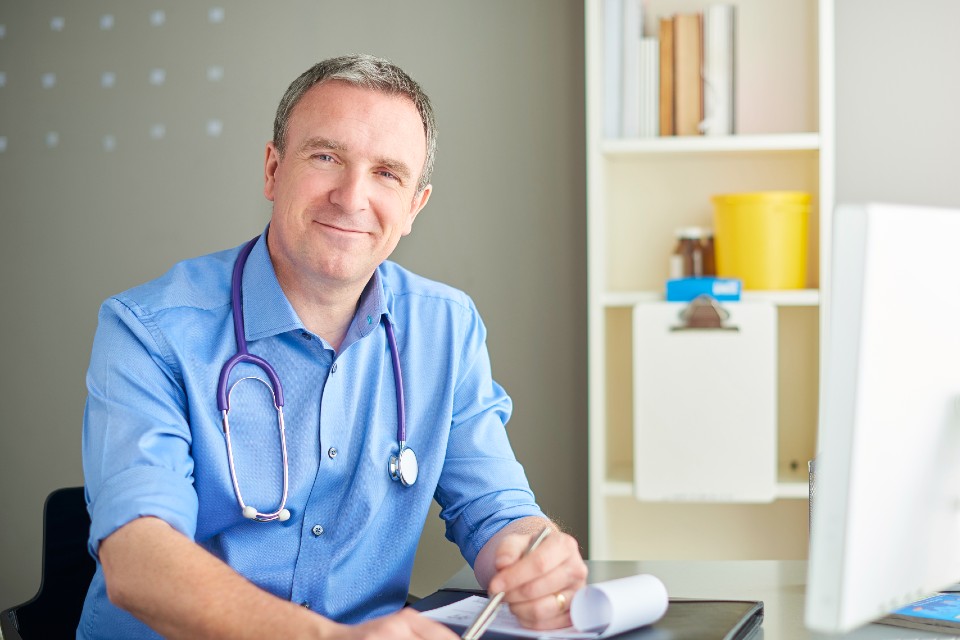 Male medical professional in office with paperwork and pen