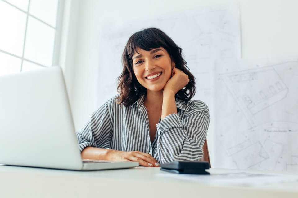 Young professional woman with laptop smiling at desk