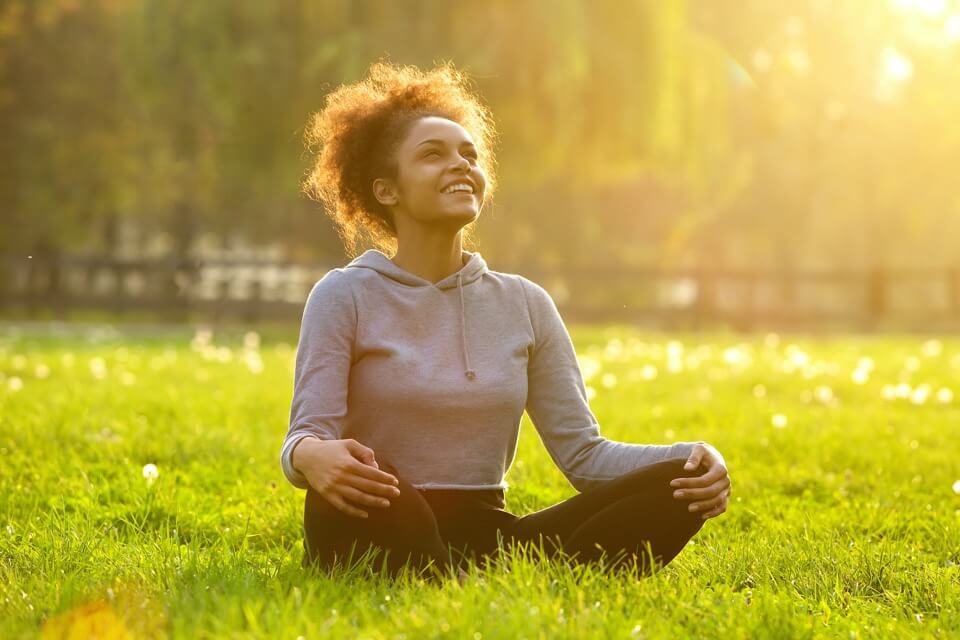 Young woman sitting in a yoga park smiling