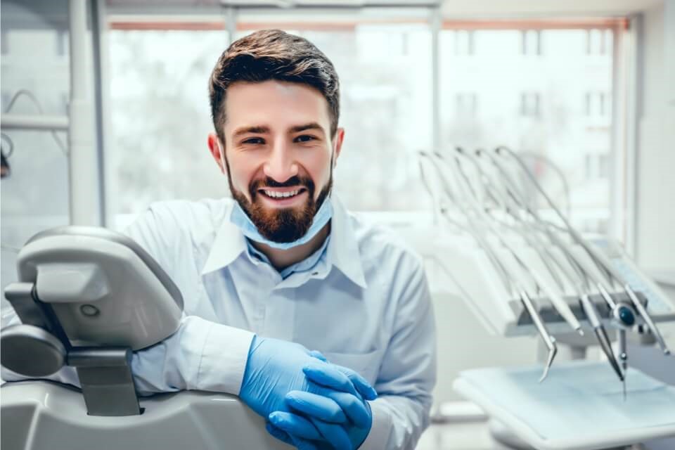 Young male dentist sitting in chair smiling