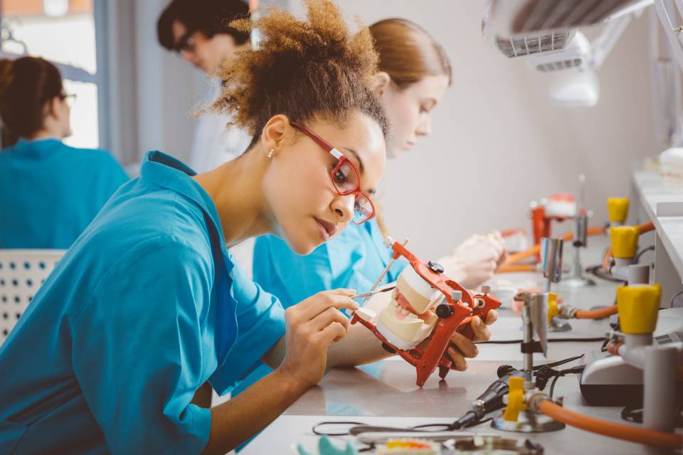 Dental students wearing scrubs working on teeth moulds