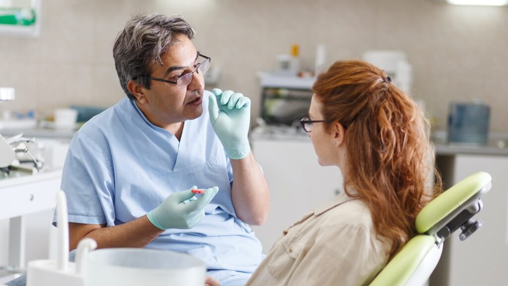Male dentist speaking to female patient