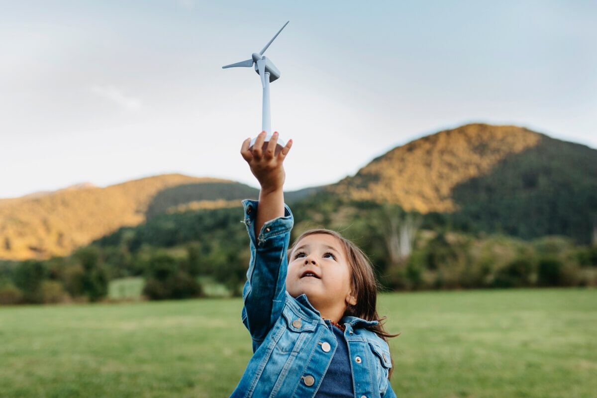 billboard-year-in-review-sustainable-mutual Young girl in the countryside holding up a toy windmill