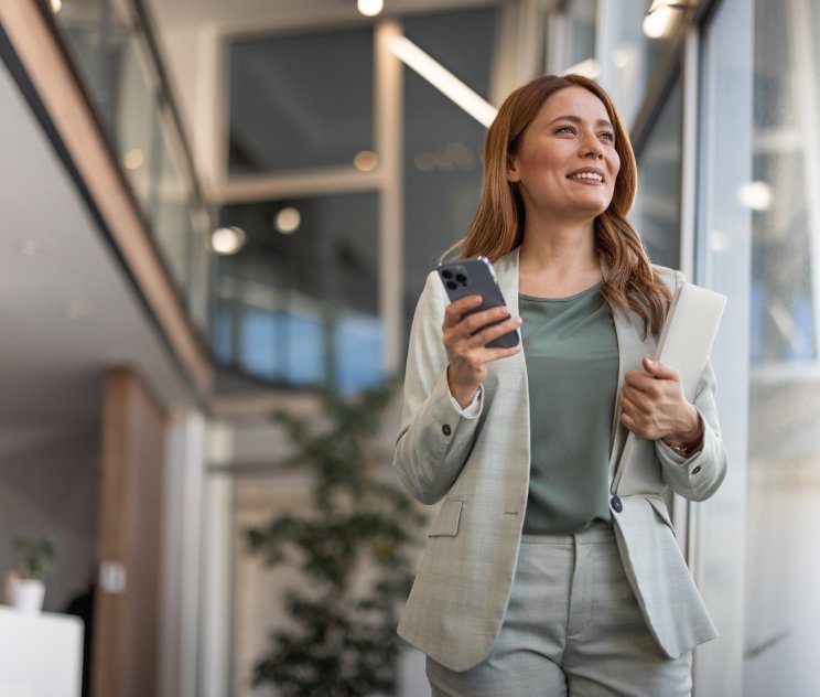 Female looking up and smiling and holding a phone and notebook Female looking up and smiling and holding a phone and notebook