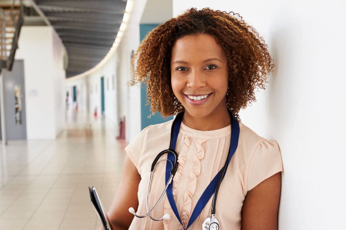 Female medic standing against wall holding clipboard Female medic standing against wall holding clipboard