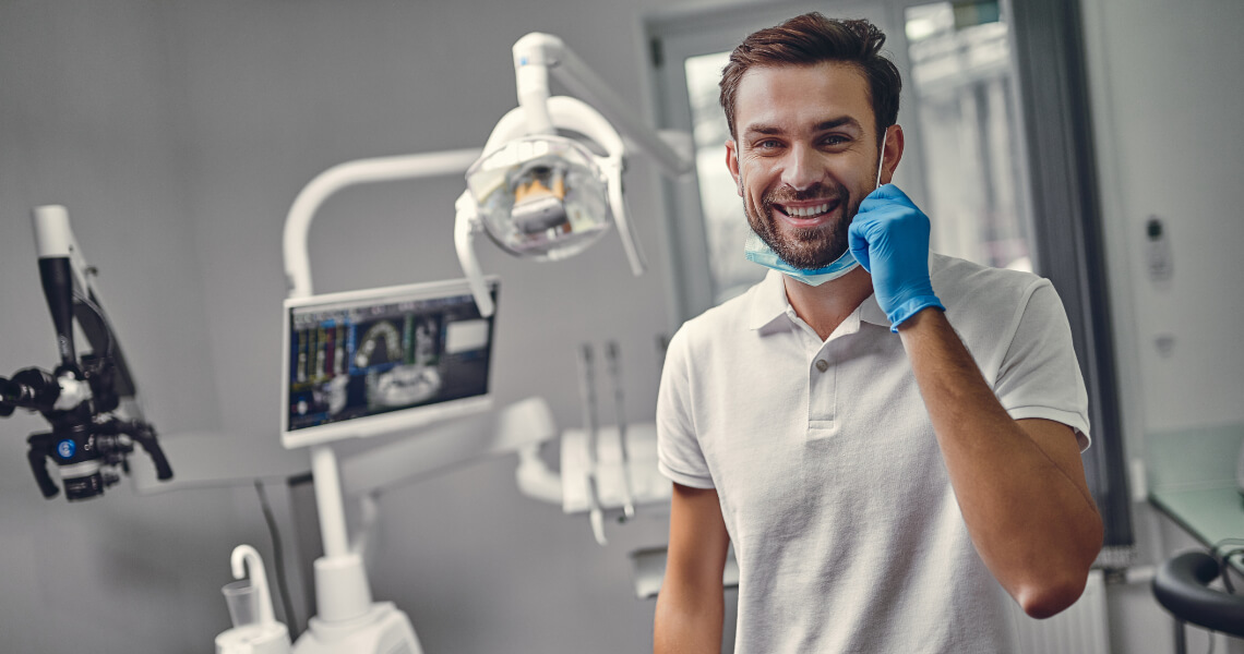 Male dentist smiling with pulled down face mask Male dentist smiling with pulled down face mask
