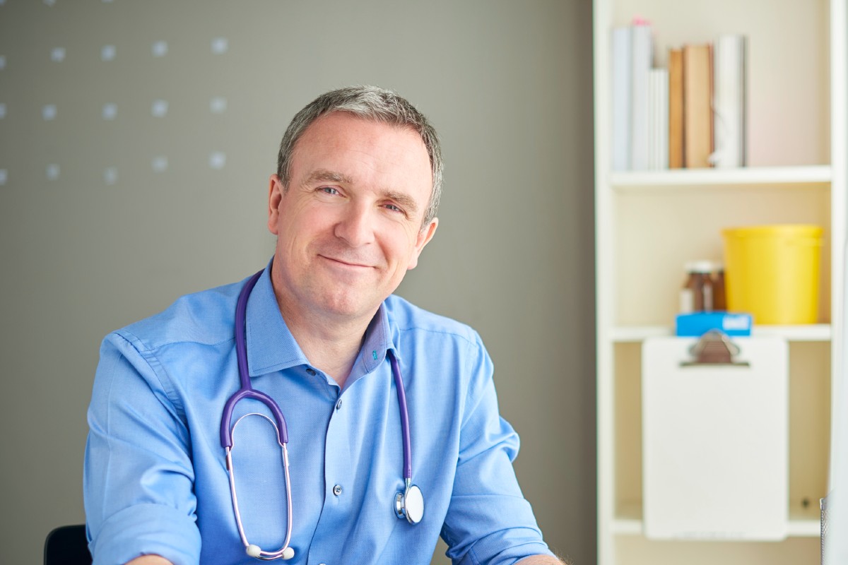 Male doctor in office with paperwork and pen Male doctor in office with paperwork and pen