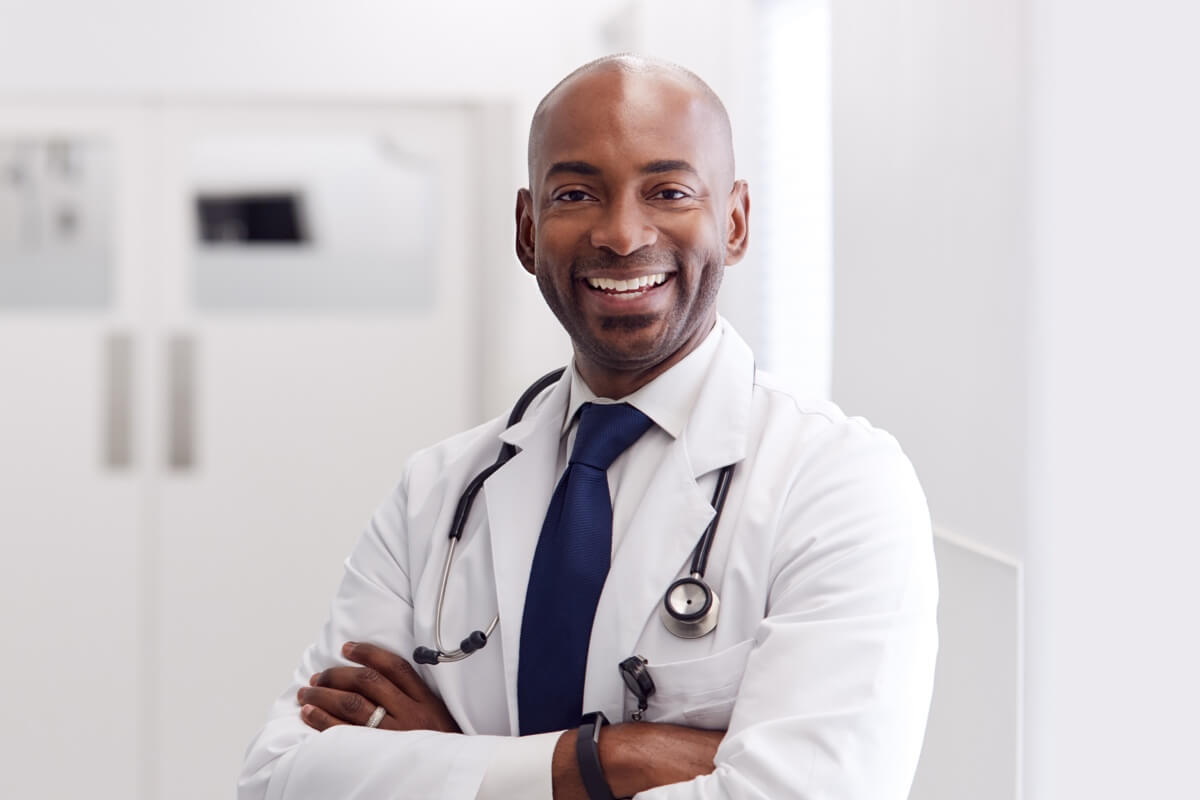 Male doctor standing in corridor smiling
