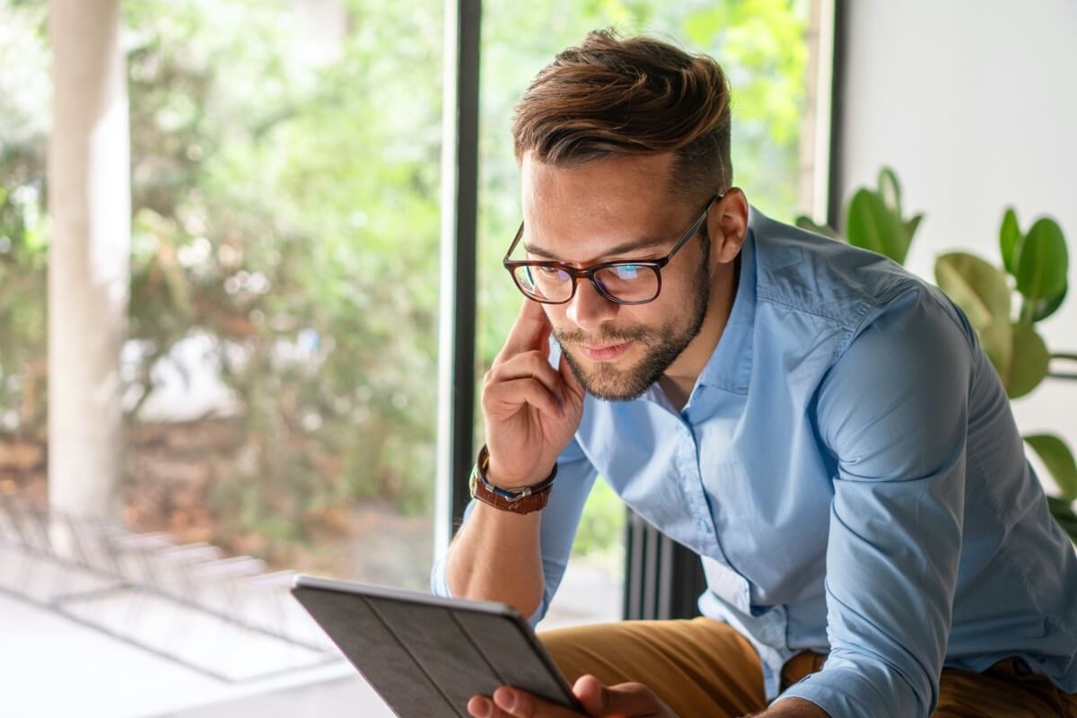 Man with glasses looking at ipad Man with glasses looking at ipad