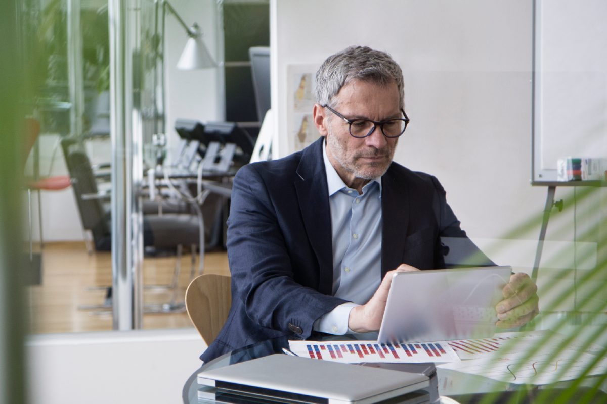 Professional man sitting at desk in office using ipad Professional man sitting at desk in office using ipad