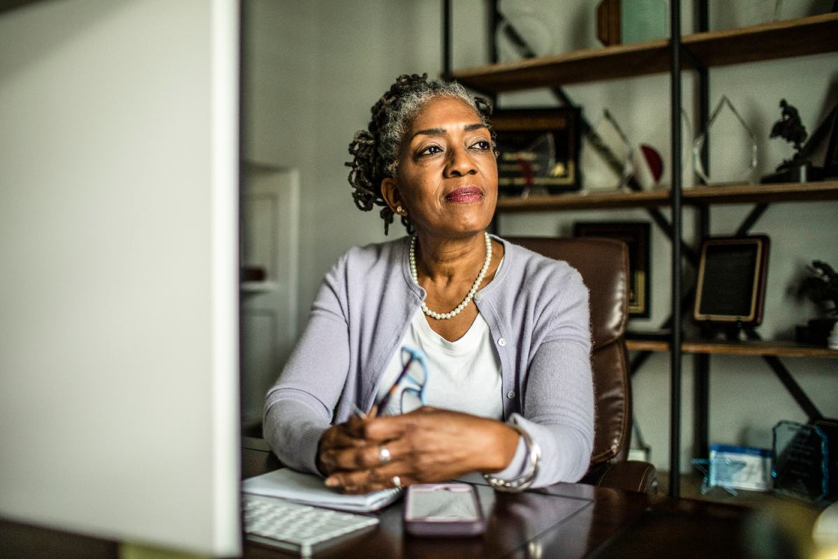Professional mature woman in home office looking out window Professional mature woman in home office looking out window