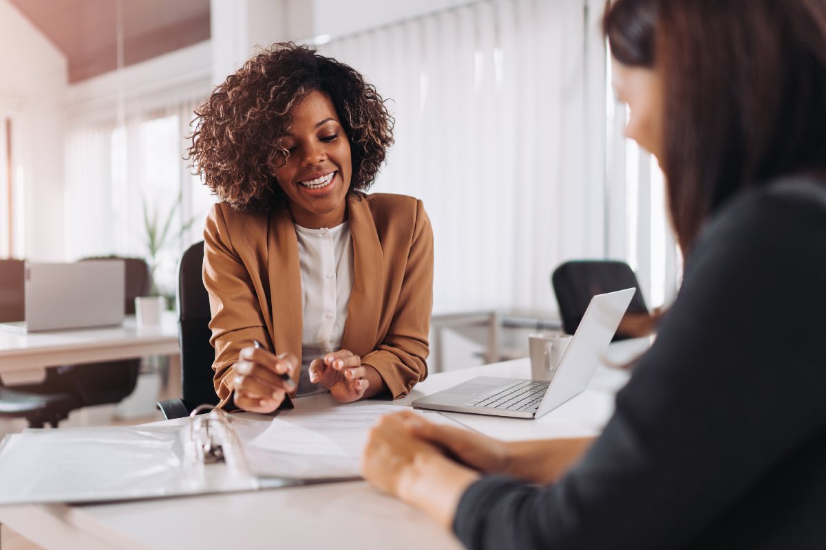 Professional woman in office with paperwork talking to customer