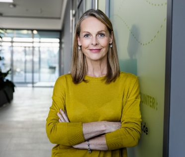 Professional woman leaning against wall in office building smiling Professional woman leaning against wall in office building smiling