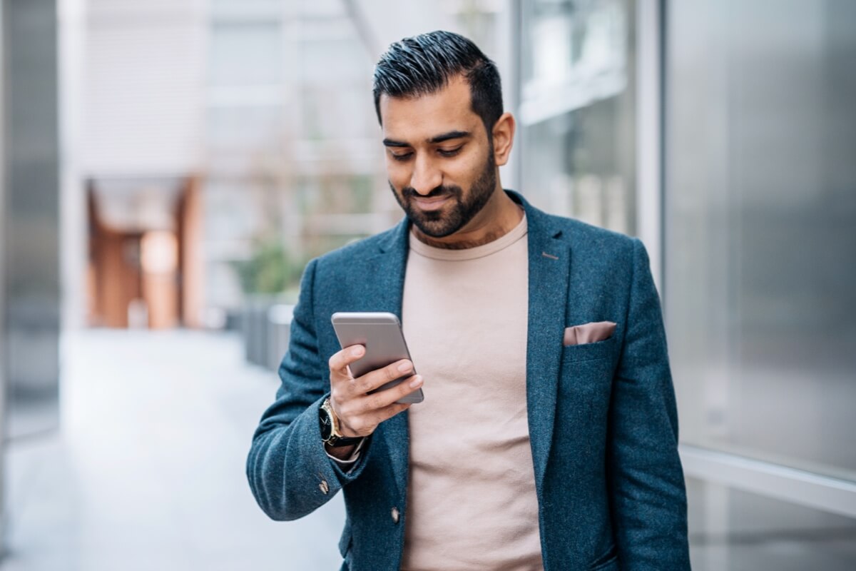 Smartly dressed Asian man smiling down at phone Smartly dressed Asian man smiling down at phone