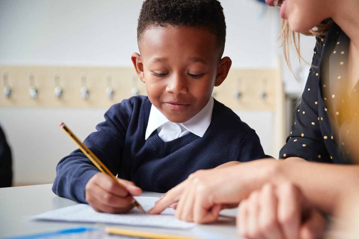 School boy writing with teacher School boy writing with teacher