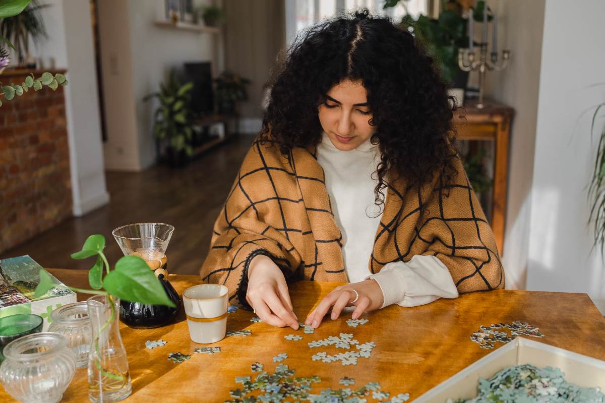 Woman sitting at table working on a puzzle Woman sitting at table working on a puzzle