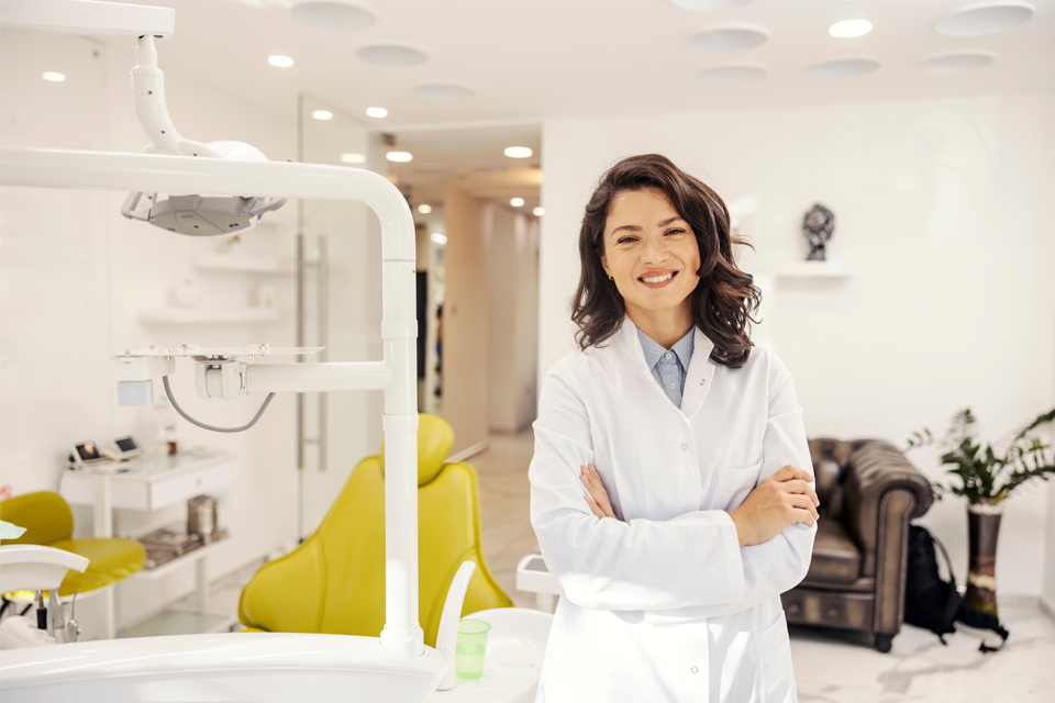 Smiling female dentist standing in front of dentist chair