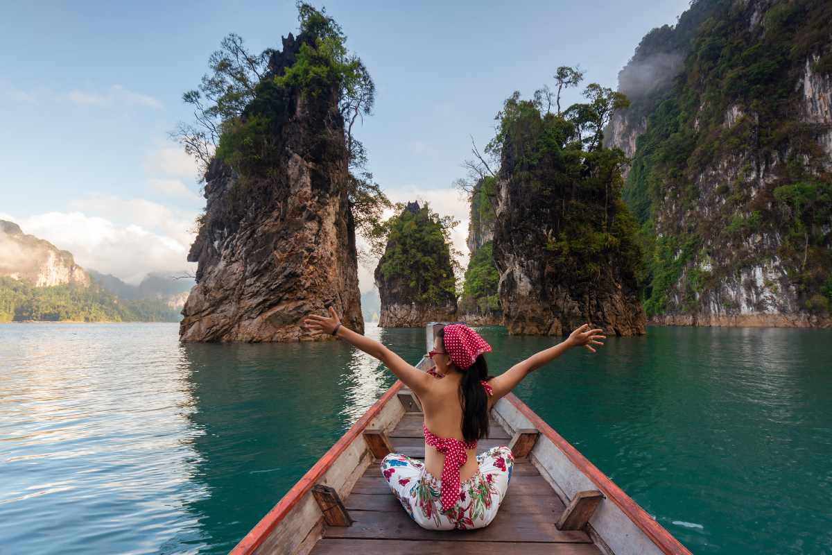 Woman sitting on boat on lake with open arms Woman sitting on boat on lake with open arms
