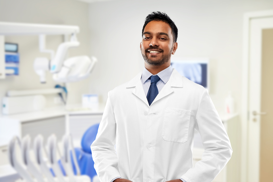 Confident dentist standing in front of dentist chair