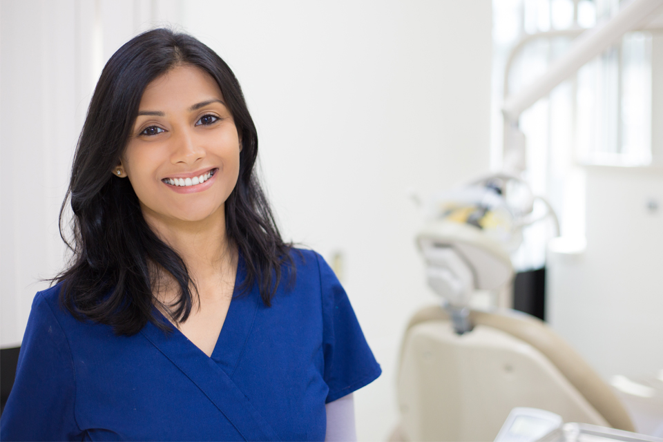 Young female dentist in scrubs smiling