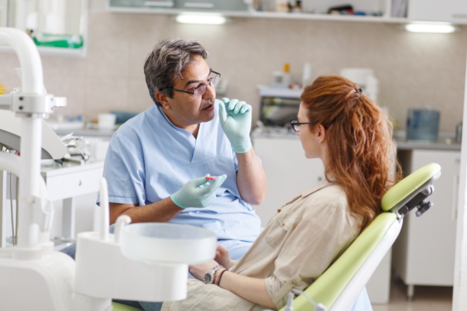 Male dentist talking with patient in chair