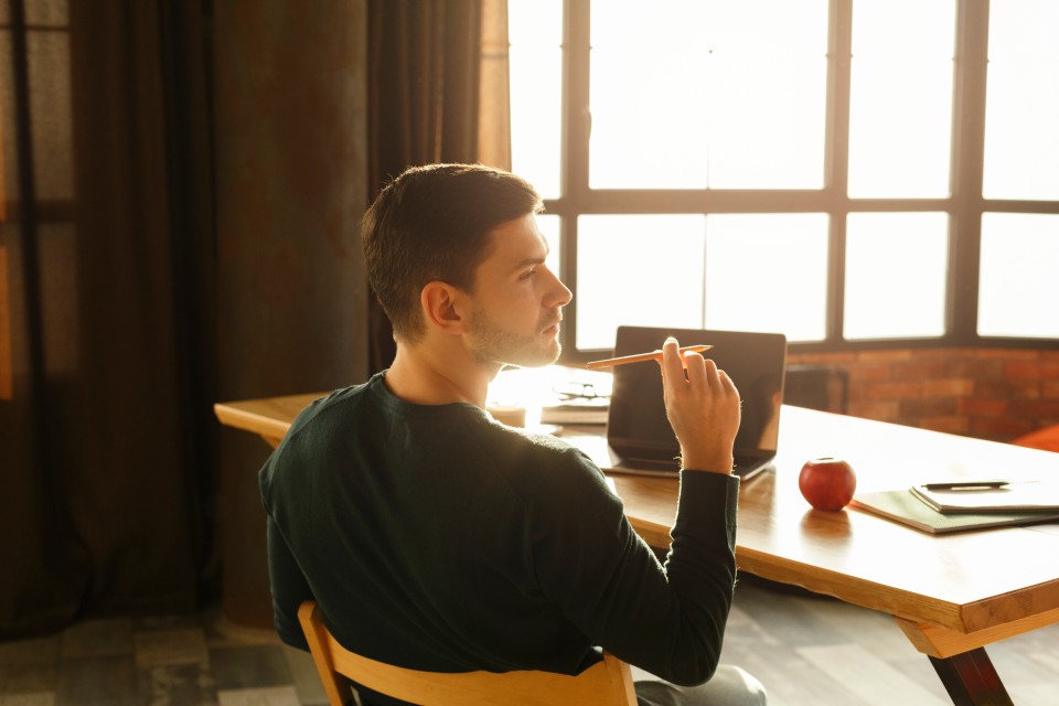 Man sitting at table holding pencil