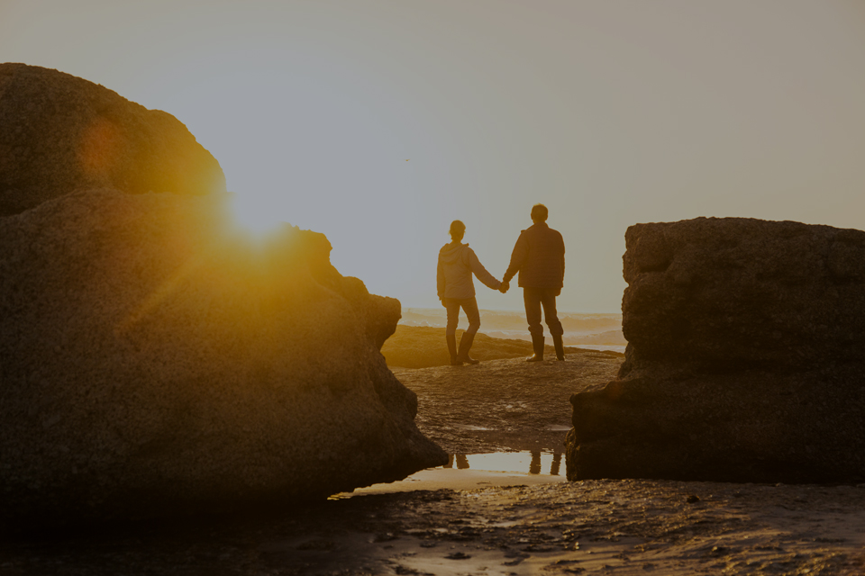 Silhouette of couple looking at sunset at top of hill