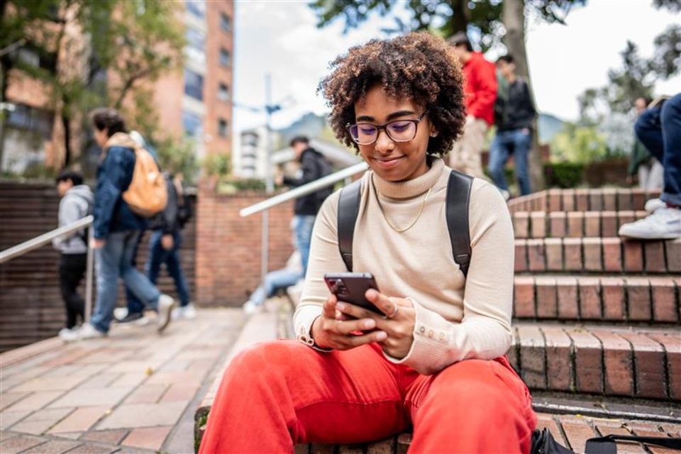 Female student sitting on steps using phone