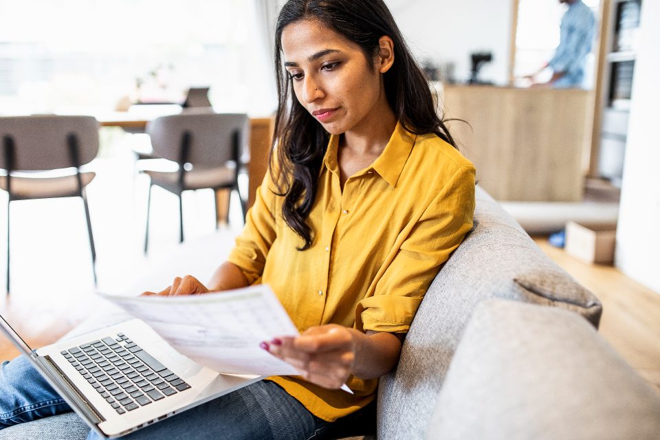 Female student with laptop and papers on sofa
