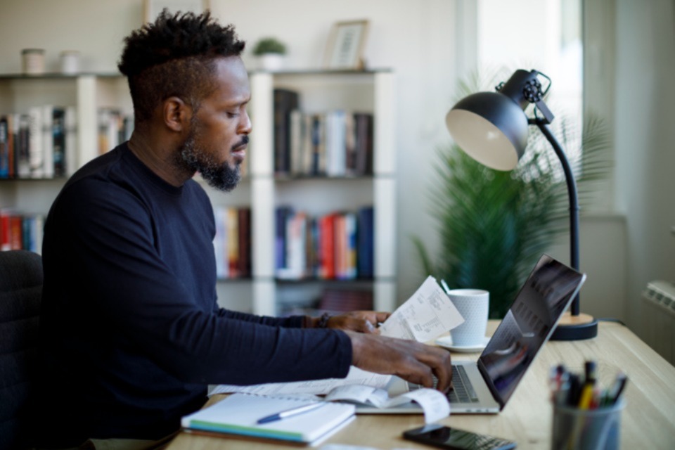 Man sitting at desk with receipts and laptop
