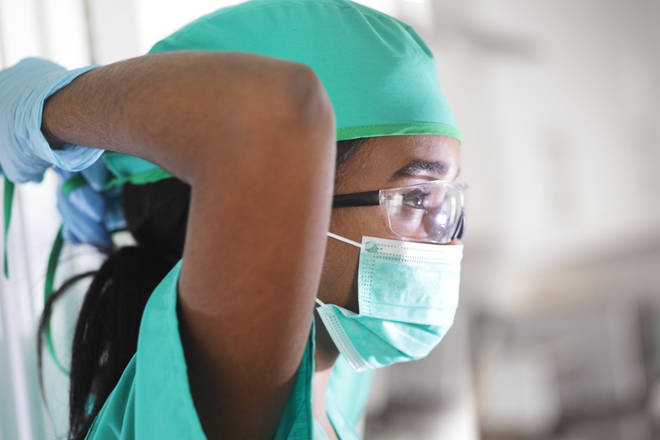 Student in scrubs and glasses taking off mask