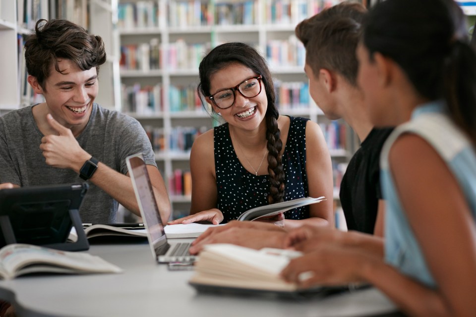 Group of students sitting in library laughing together