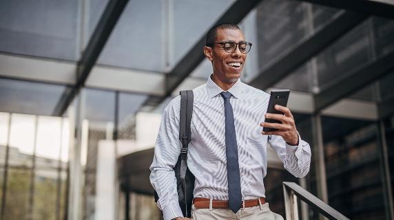 Professional man walking outside smiling at phone