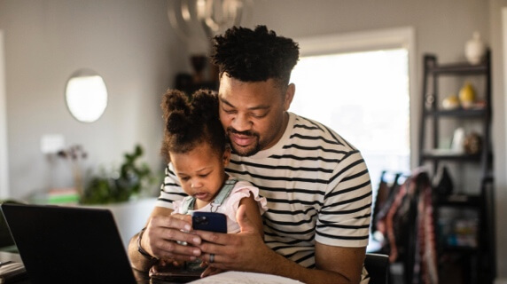 Father and daughter at home looking at phone