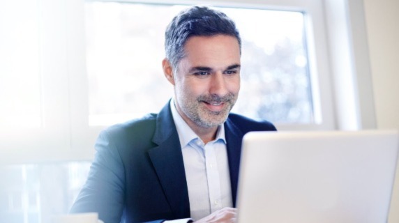 Mature businessman looking at laptop smiling