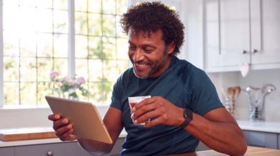 Mature male by kitchen counter with tablet and coffee
