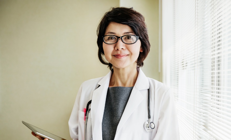 Female medical professional wearing white coat and holding tablet