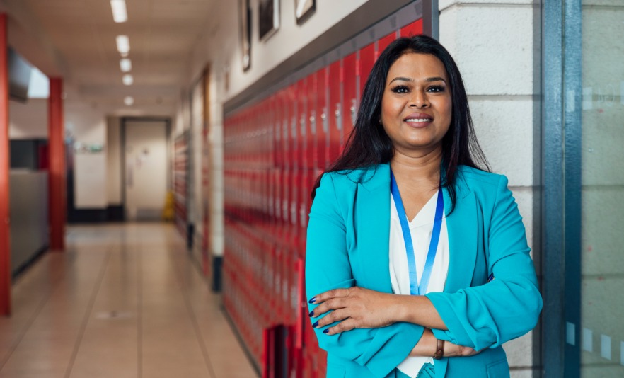 Female teacher standing in corridor in front of lockers