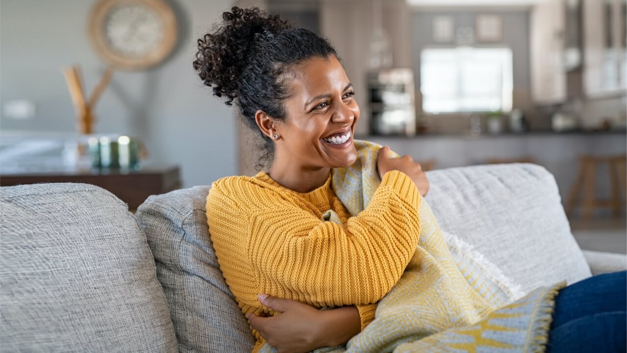 hero-happy-female-sitting-on-sofa-in-home Happy female sitting on sofa in home