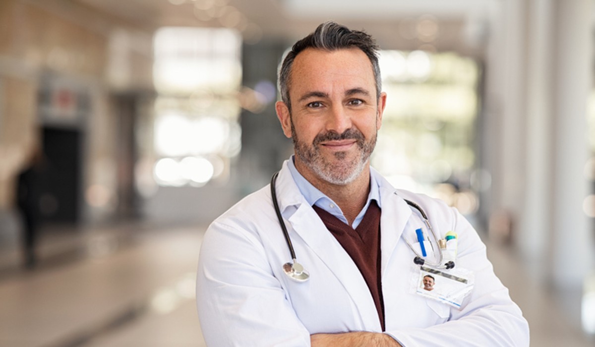 Male doctor standing in corridor with crossed arms Male doctor standing in corridor with crossed arms