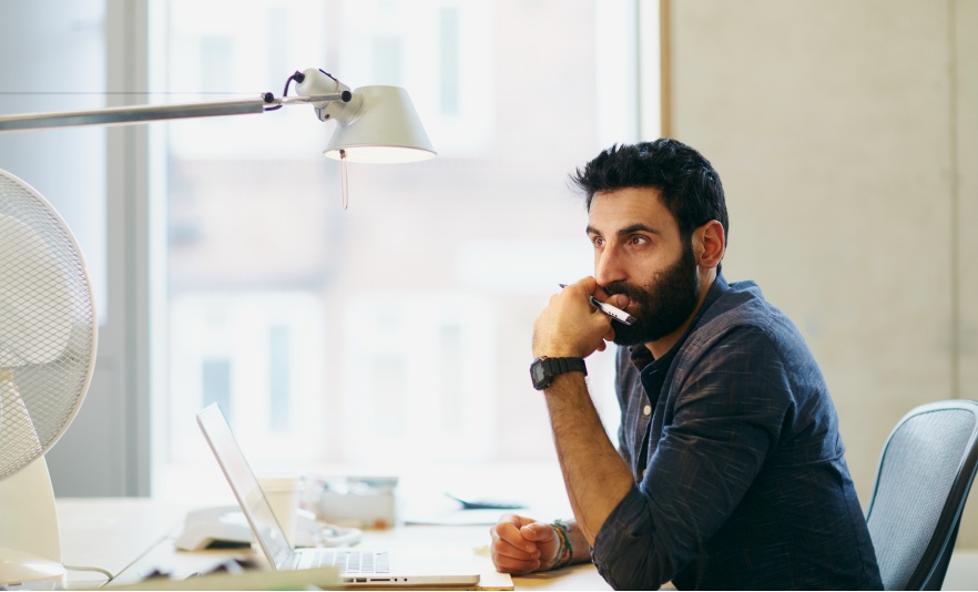 Professional man sitting at office desk in thought