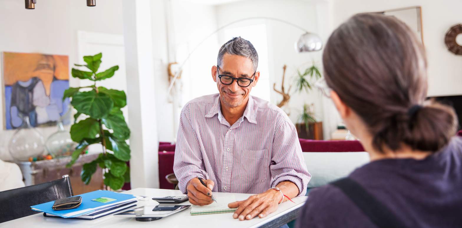 Professional man sitting with customer on table with paperwork (hero)